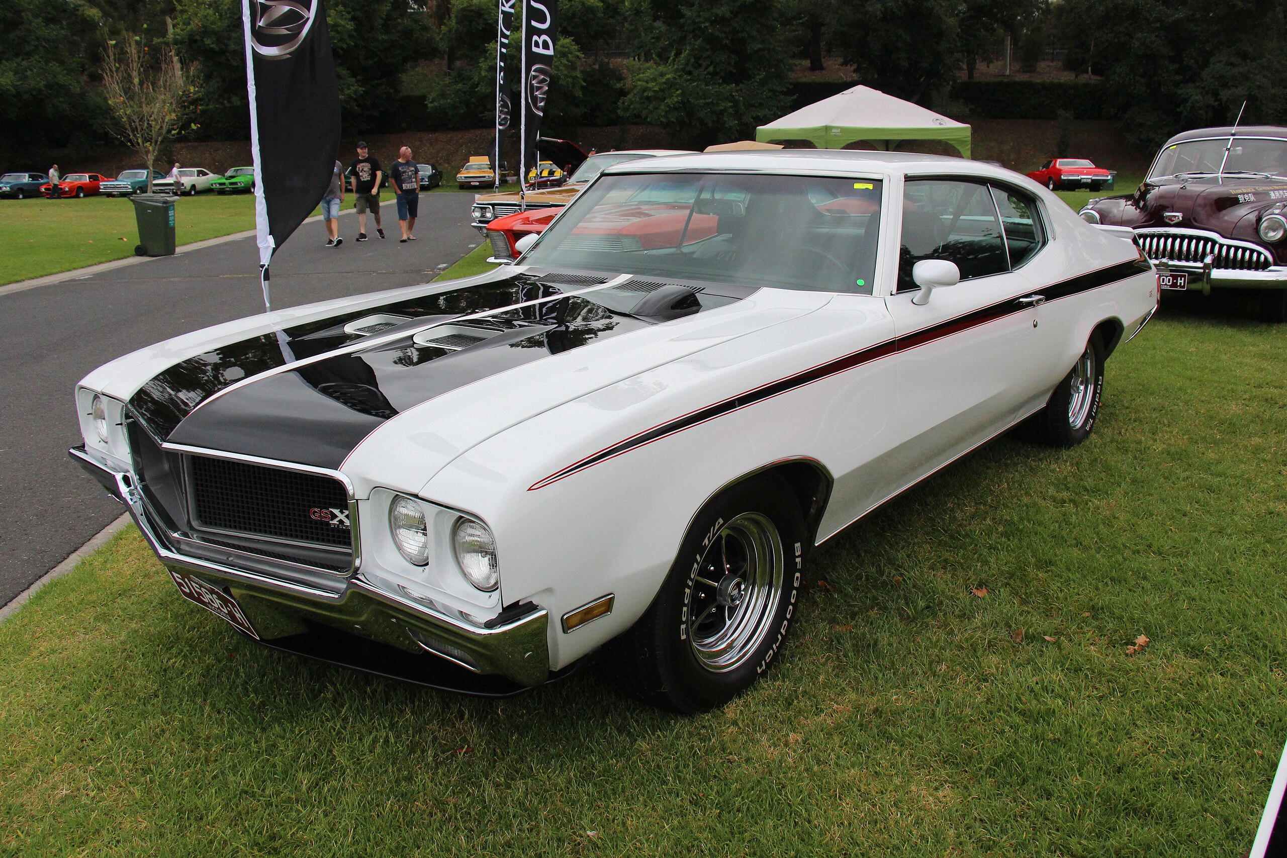 1970 Buick GSX 455 Coupe in Apollo White with black hood stripe and red accent lines at a classic car show