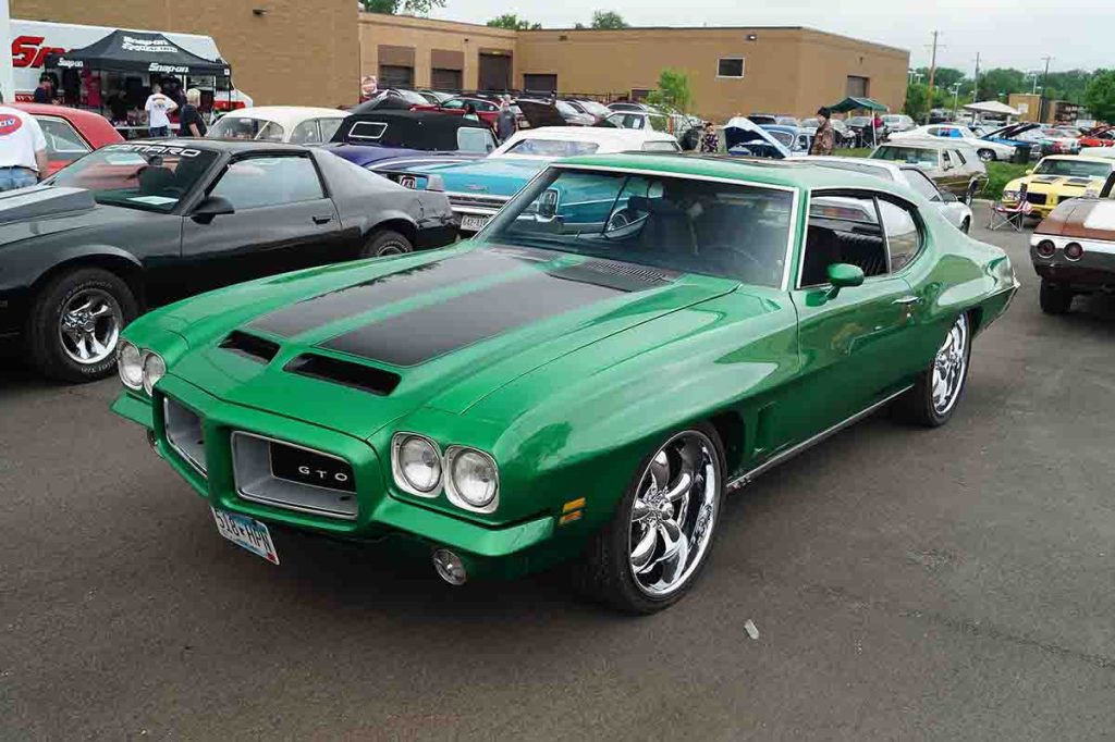 Classic 1972 Pontiac GTO in vibrant green with black hood striping at a muscle car show.